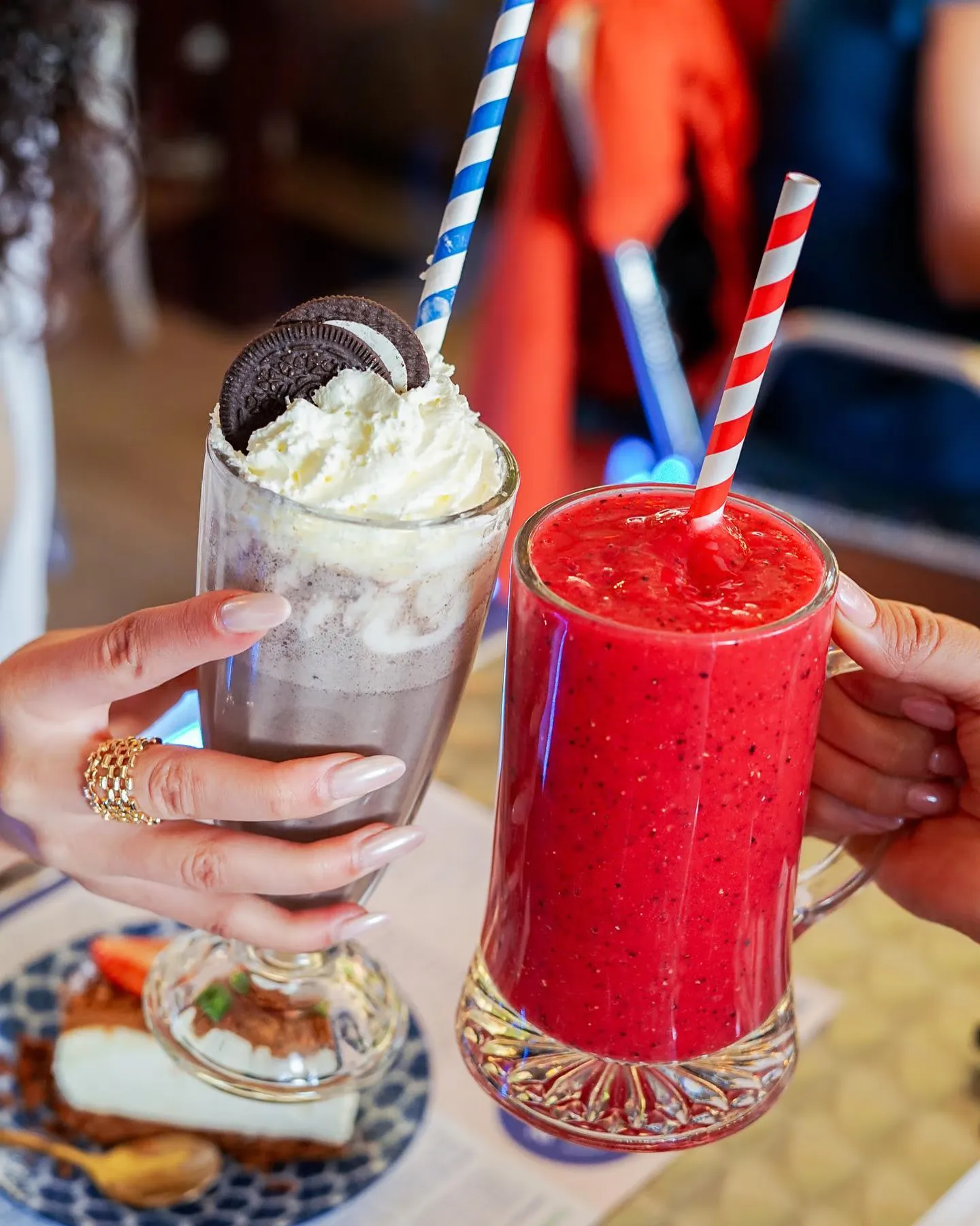 Imagen de dos manos brindando con un milkshake y un batido de frutas